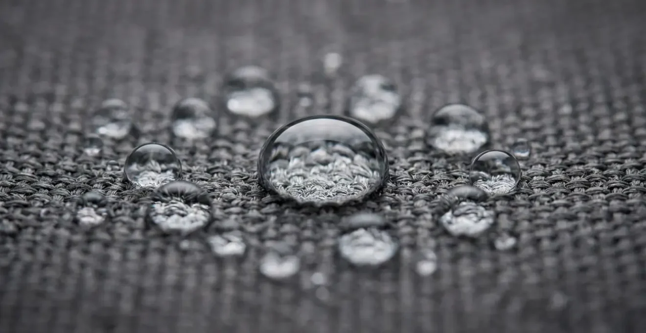 Detalle macro de gotas de agua formando perlas sobre superficie de lona tratada